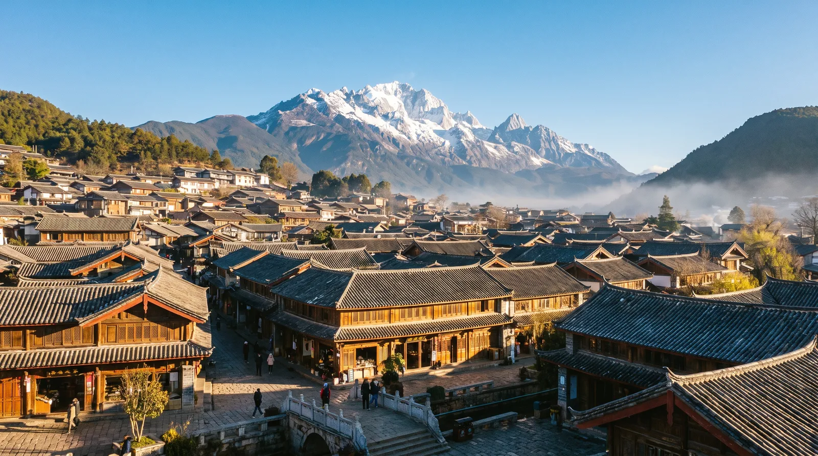 Lijiang old town with Jade Dragon Snow Mountain behind, tiled rooftops, clear blue sky, crisp morning light