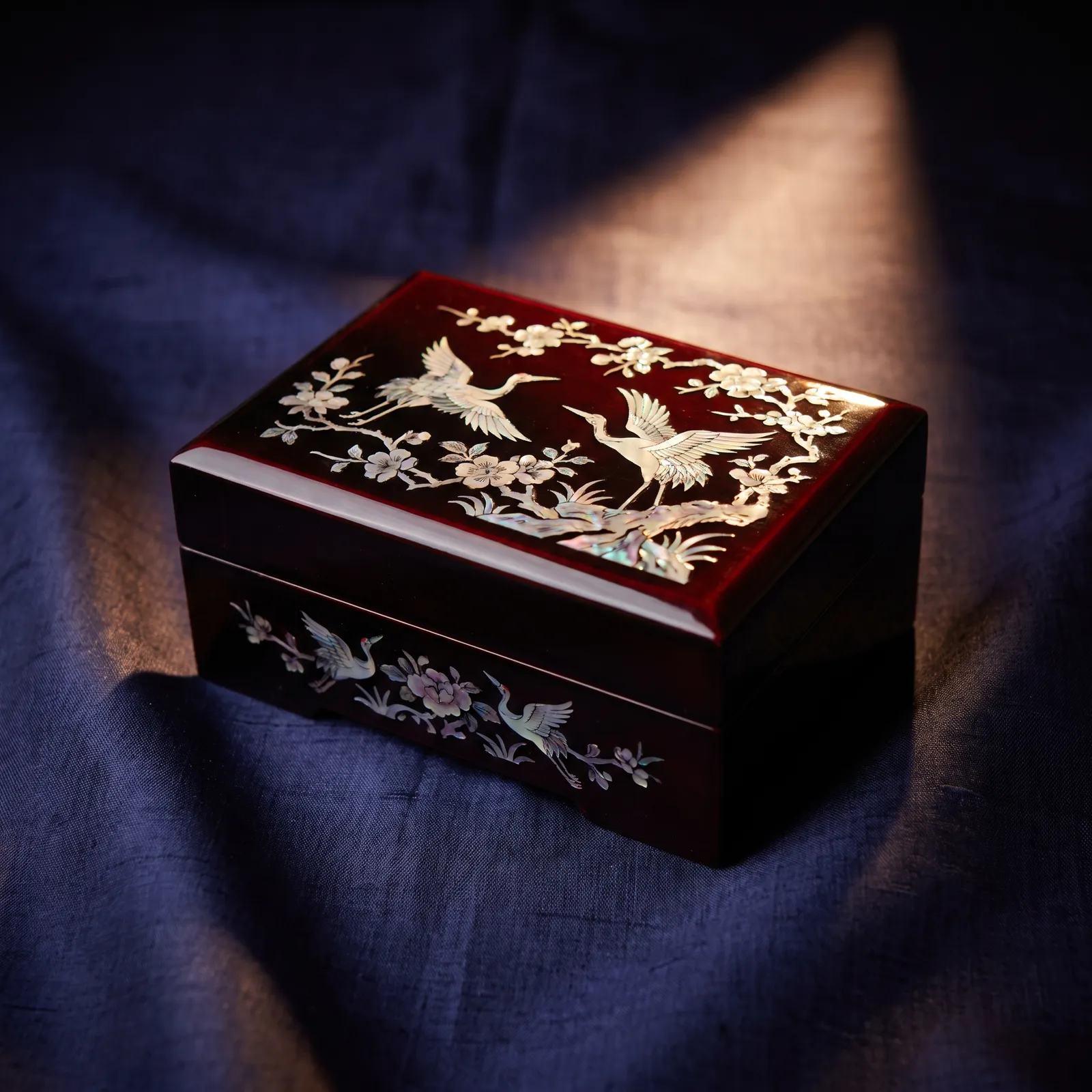 Korean traditional otchil lacquer jewelry box with mother-of-pearl inlay, on dark silk, dramatic spot lighting