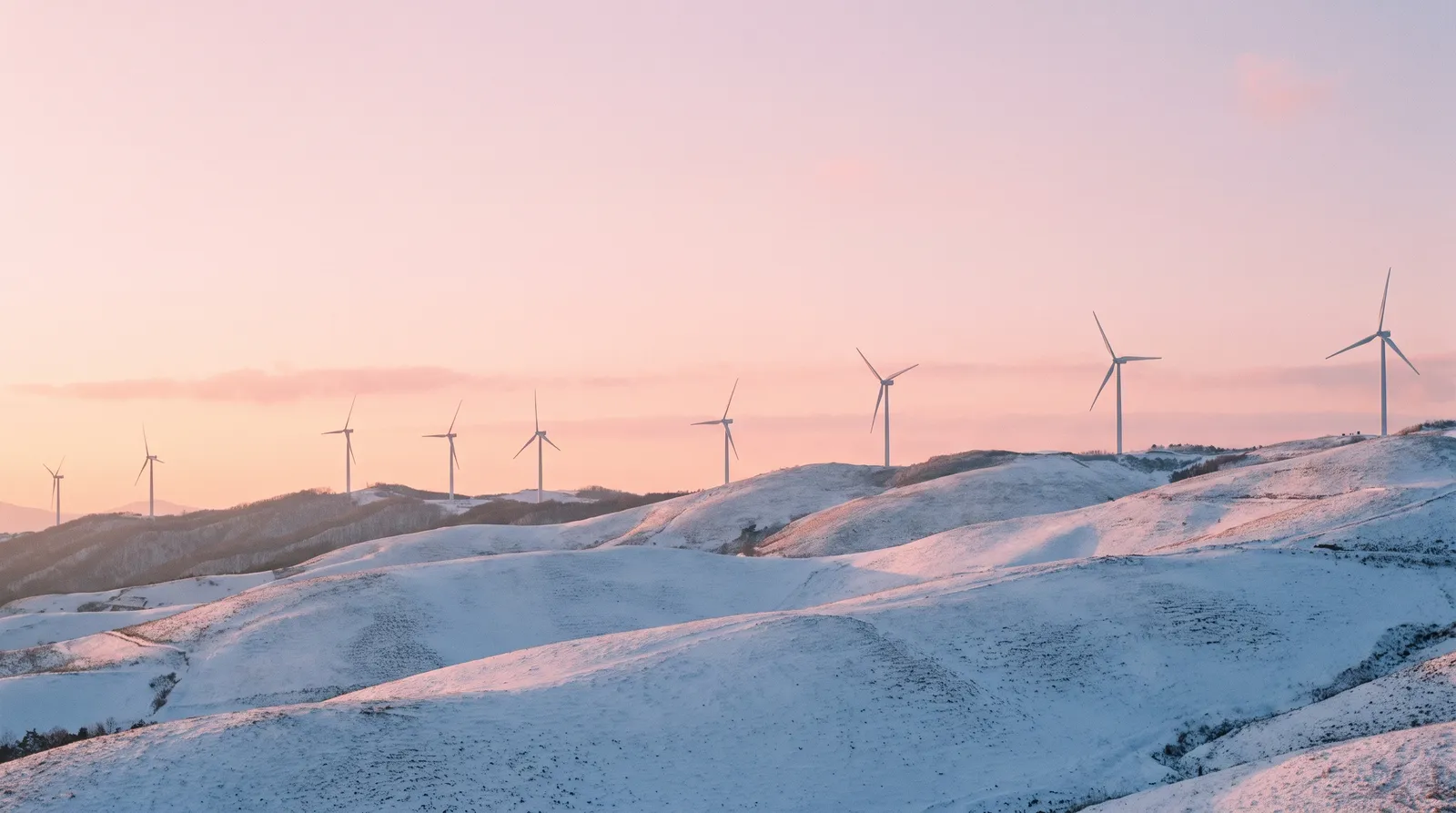 First snow on the rolling hills of Daegwallyeong in Gangwon-do at dawn, a line of wind turbines along the ridge, pastel pink sky, soft blue shadows, quiet minimal landscape photography
