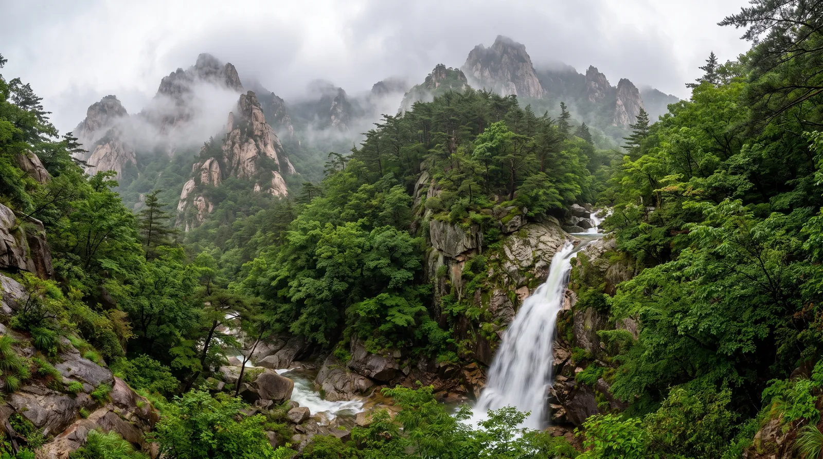 Seoraksan national park in summer after rain, granite peaks wrapped in cloud, a waterfall roaring into a green gorge, fresh vivid landscape photography