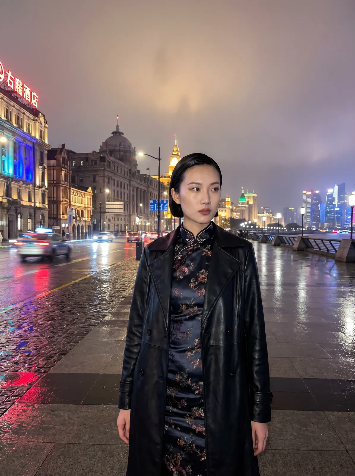 Shanghai model in a reinterpreted silk qipao with a leather trench layered over it, standing on the Bund at night, wet pavement reflecting neon, dramatic flash plus ambient blur, fashion week street-s