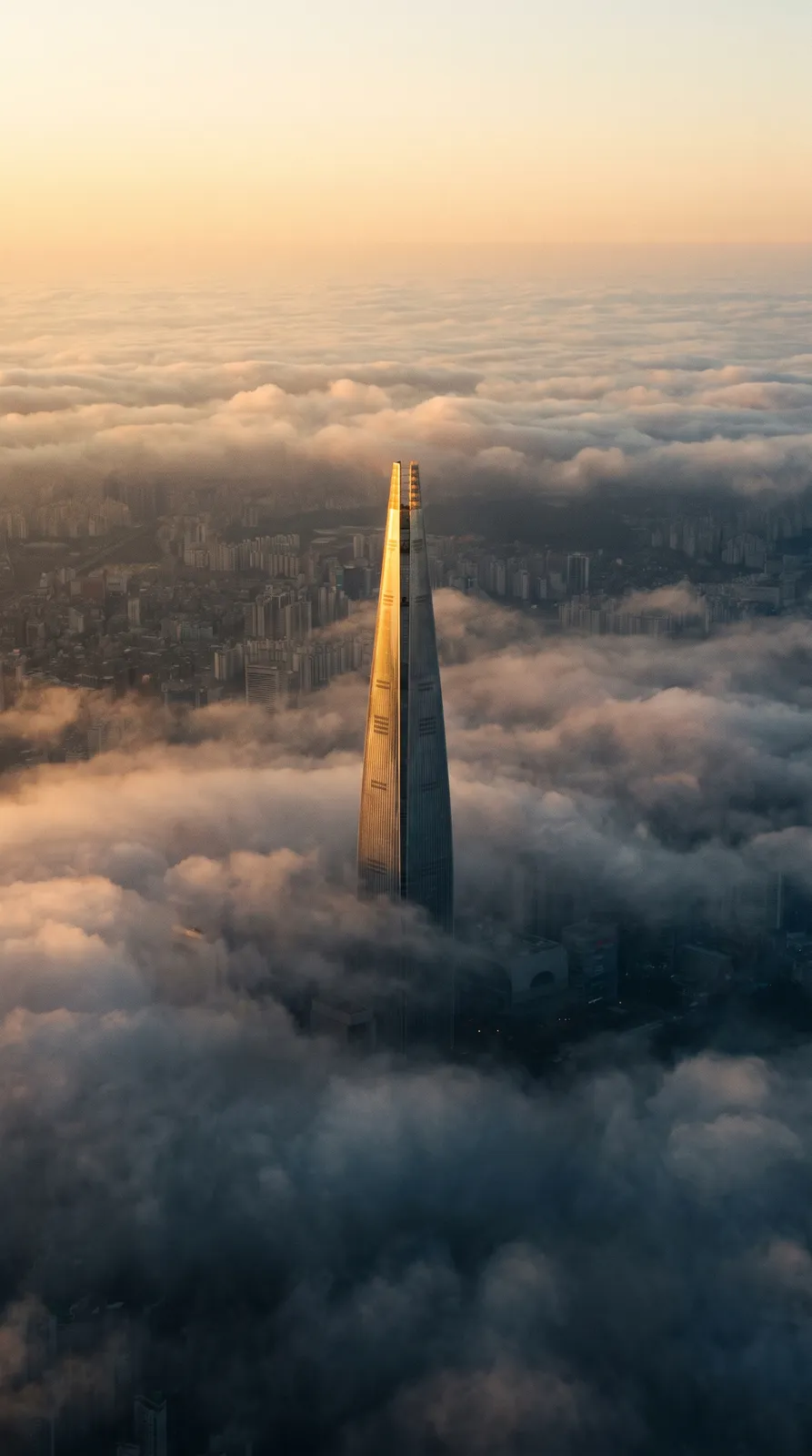 Vertical wallpaper of Seoul's Lotte Tower piercing low clouds at sunrise, dramatic but minimal