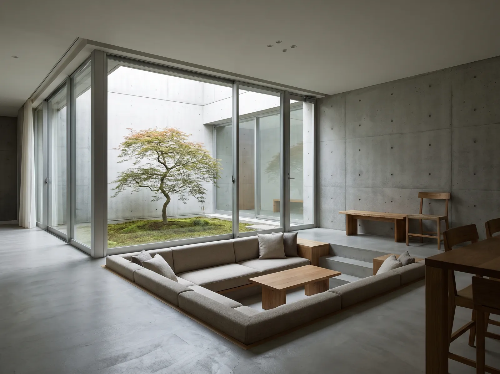 Minimal concrete house living room in Japan with a sunken seating area and a courtyard tree visible through glass, calm architecture photography