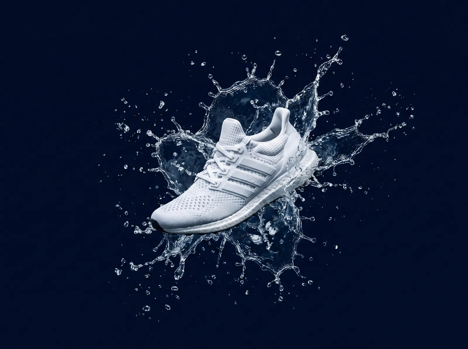 White running sneaker suspended mid-air with splashing water frozen around it, dark navy background, high-speed photography, dynamic sports product shot