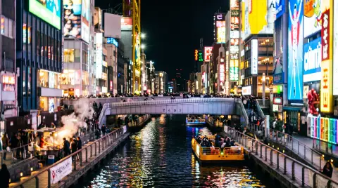Osaka Dotonbori canal at night, glowing signs reflected in the water without readable text, crowds on the bridge, vibran
