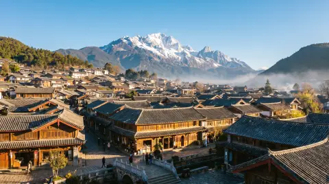 Lijiang old town with Jade Dragon Snow Mountain behind, tiled rooftops, clear blue sky, crisp morning light