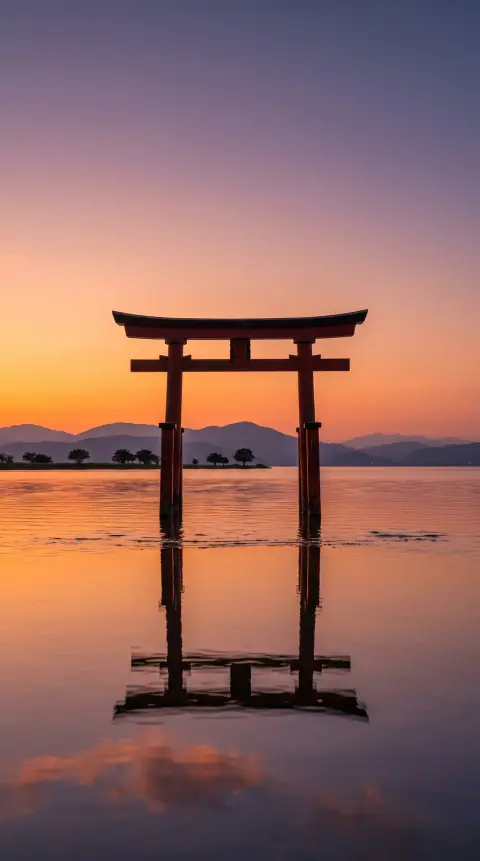 Phone wallpaper of a red torii gate standing in shallow water at sunset, calm reflections, minimal composition, warm ora