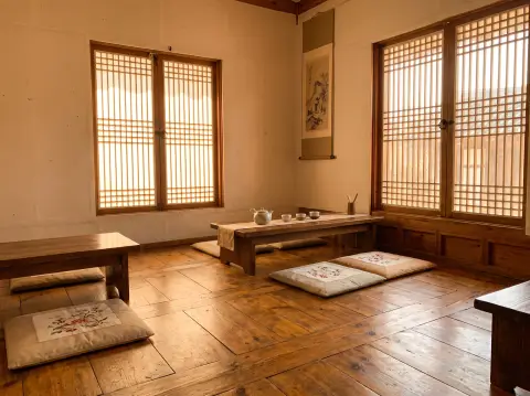 Korean ondol-floored traditional room converted into a modern tea house, low cushions, paper windows glowing, minimal de