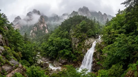 Seoraksan national park in summer after rain, granite peaks wrapped in cloud, a waterfall roaring into a green gorge…