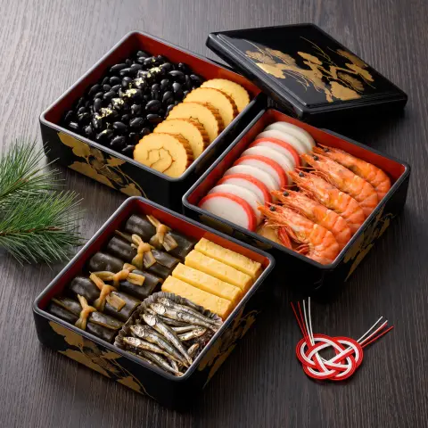 Food photography of a three-tier lacquered osechi box for New Year, glossy black beans, rolled omelette…