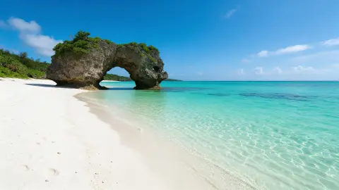 Okinawa emerald beach with white sand and a rocky arch, crystal clear water, bright tropical afternoon